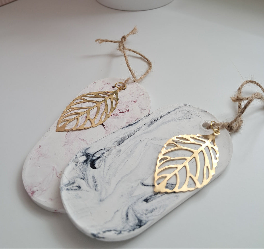 Decorative hanging tags with gold leaf designs on a marble surface.