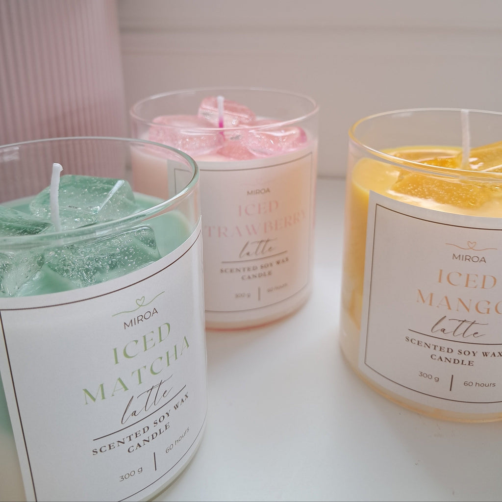Three scented candles labeled 'ICED MATCHA Latte', 'ICED STRAWBERRY Latte', and 'ICED MANGO Latte' on a white surface.
