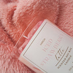 Scented candle labeled 'ICED STRAWBERRY LATTÉ' on a pink textured surface