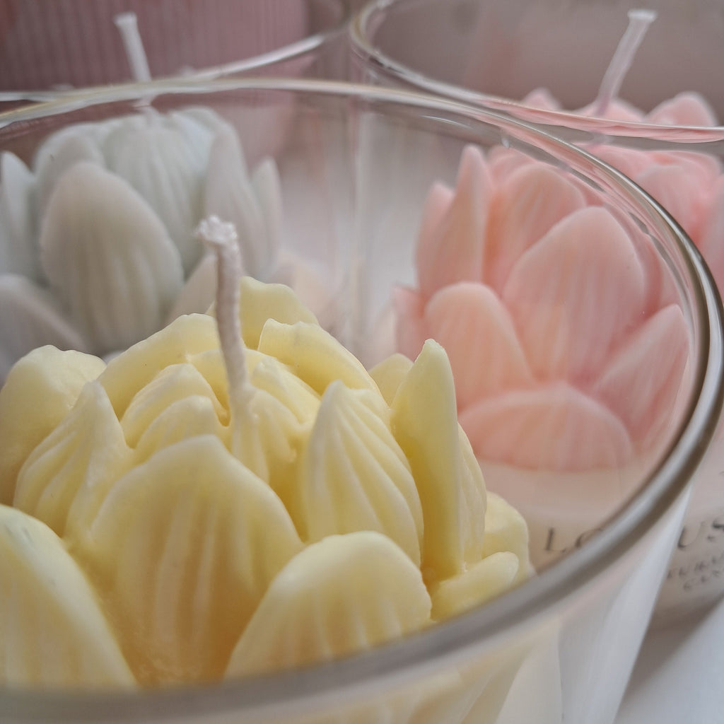 Close-up of pink, yellow, and white flower-shaped bath bombs in a glass bowl.