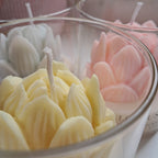 Close-up of pink, yellow, and white flower-shaped bath bombs in a glass bowl.