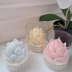 Decorative candles with floral designs on a white surface, surrounded by flowers.